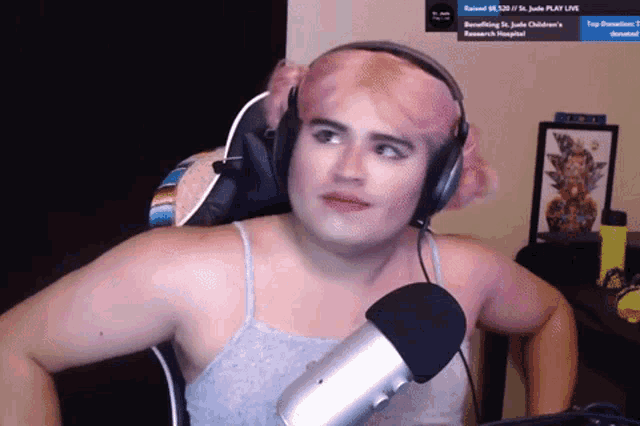a man wearing headphones and a pink wig looks at the camera