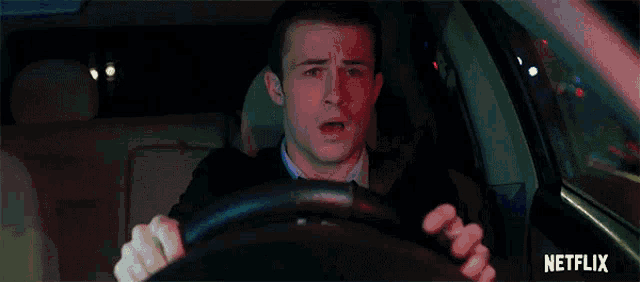 a man is driving a car at night with a netflix logo behind him