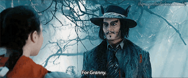 a man in a cat suit talks to a little girl who is wearing a red riding hood