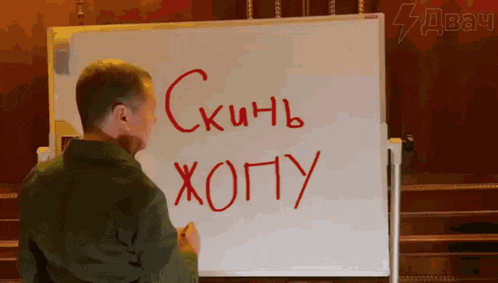 a man stands in front of a whiteboard that says " skinb xopy " in red marker