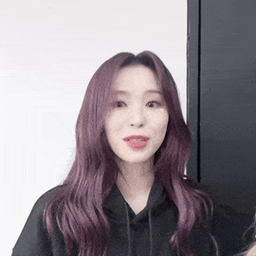 a woman with purple hair is wearing a black sweatshirt