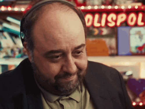 a bald man with a beard wearing headphones in front of a sign that says polispol