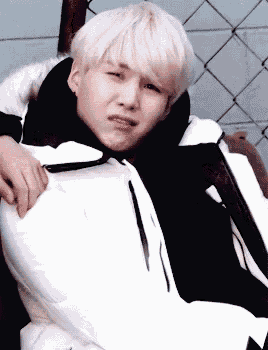 a young man with blonde hair is wearing a white jacket and black sweater