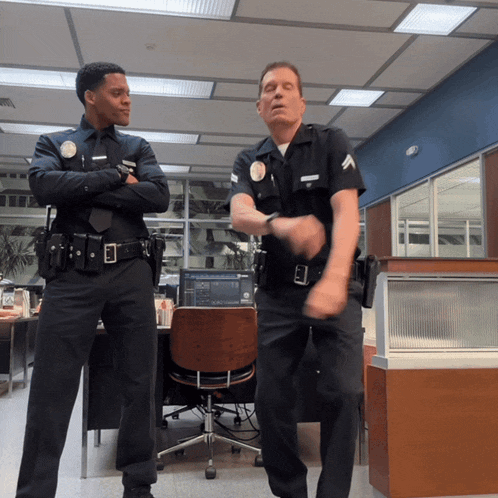 two police officers are dancing in an office with one wearing a badge that says ' l.a. '