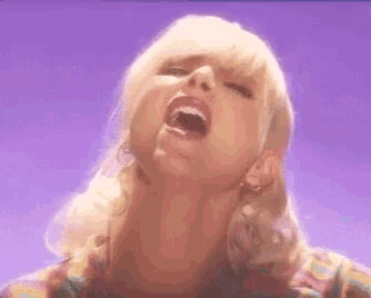 a woman with blonde hair and red lips is making a funny face with her mouth open .