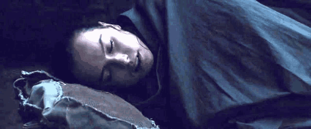 a woman is sleeping on a bed with her eyes closed