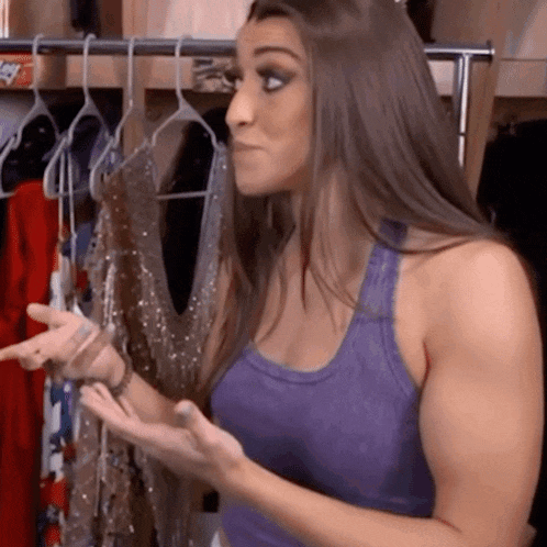 a woman in a purple tank top is standing in front of a rack of clothes ..