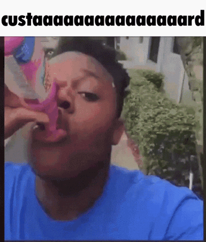 a man in a blue shirt is eating a purple item with his mouth .