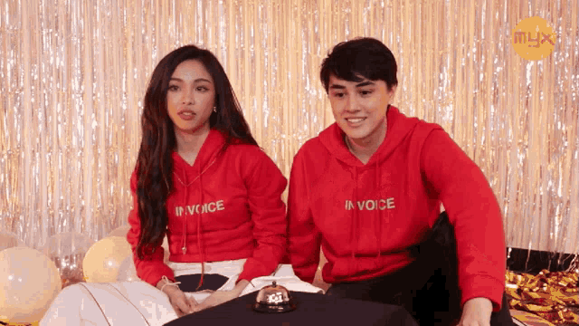 a man and a woman wear red hoodies that say in voice