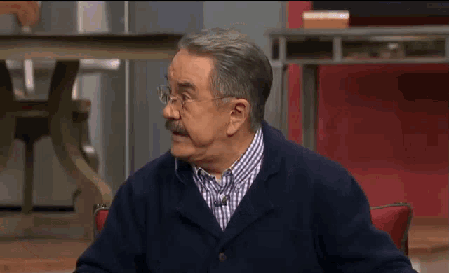 a man with glasses and a mustache is sitting in a chair with his eyes closed