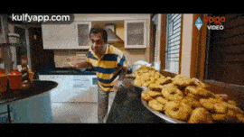 a man in a striped shirt is standing in front of a counter filled with food .