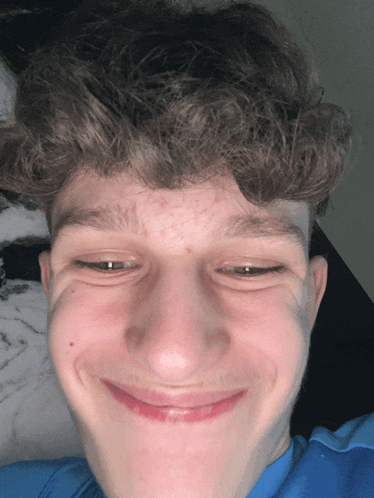a young man with curly hair makes a funny face with his eyes closed