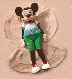 a mickey mouse doll is laying in the sand on the beach