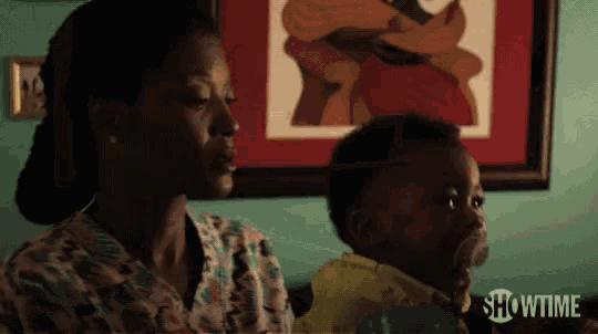 a woman is holding a baby in front of a showtime picture