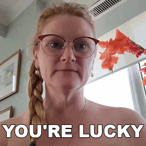a woman wearing glasses says you 're lucky in front of flowers