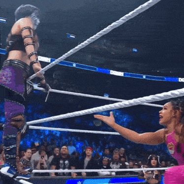 two women are wrestling in a ring with a crowd in the background