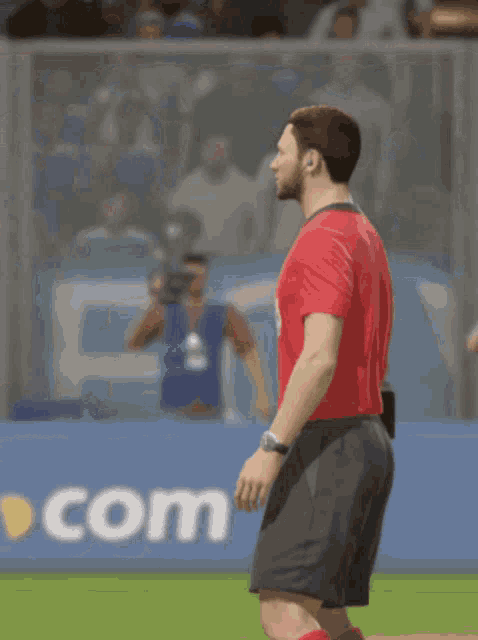 a man in a red shirt and black shorts is standing on a field