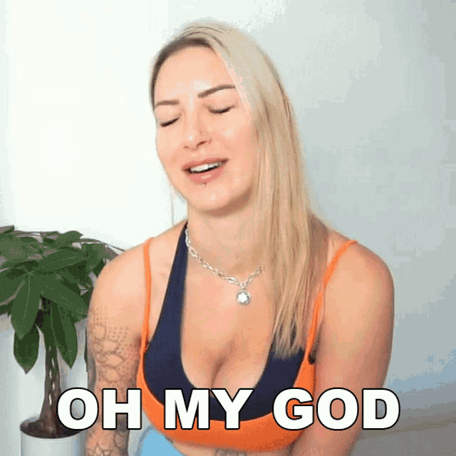 a woman in a sports bra says oh my god in front of a plant