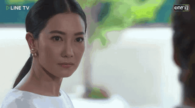 a woman in a white shirt and earrings is looking at a man .