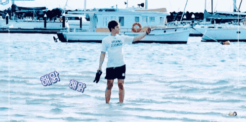 a man in a white shirt is standing in the water .