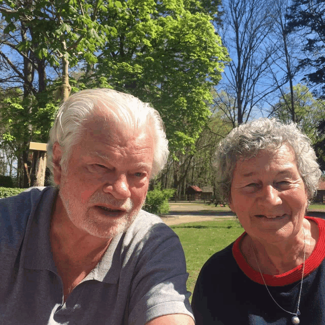 a man and woman are posing for a picture in front of trees