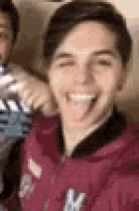 a young man is sticking his tongue out while taking a selfie .