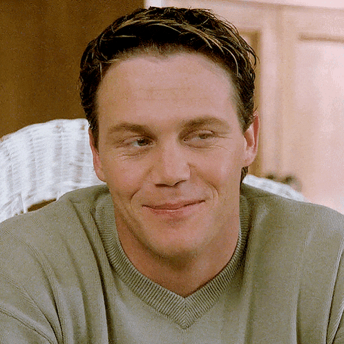a close up of a man wearing a grey sweater