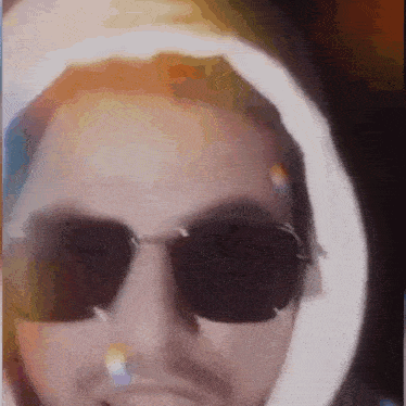 a close up of a man wearing sunglasses and a hood .