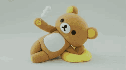 a brown teddy bear is laying on a yellow pillow