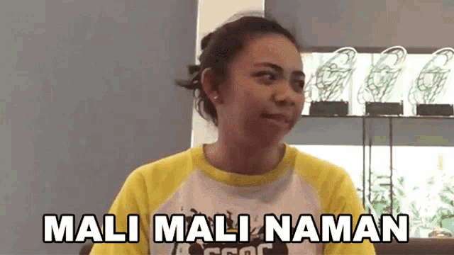 a woman wearing a yellow and white shirt says mali mali naman .
