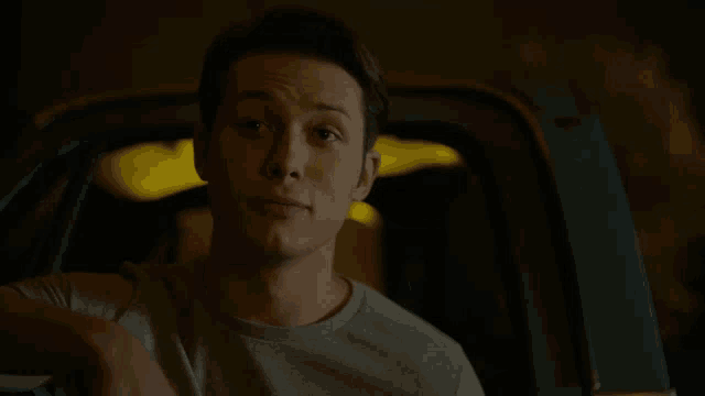 a man in a gray shirt is sitting in a car