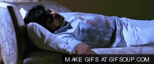 a man is laying on a couch with a make gifs at gifsoup.com link