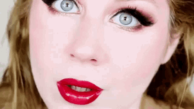 a close up of a woman 's face with blue eyes and red lipstick .