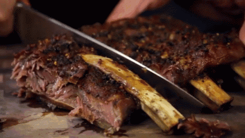 a person is cutting ribs on a cutting board with a knife