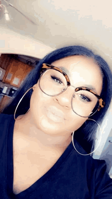 a woman wearing glasses and hoop earrings is smiling