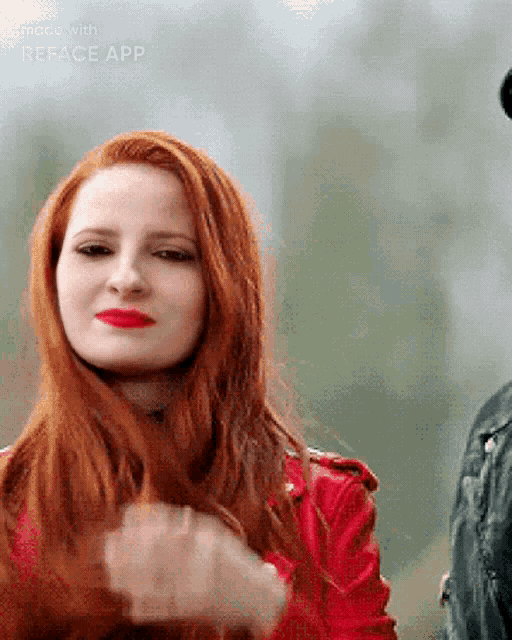 a woman with red hair is wearing a red jacket .