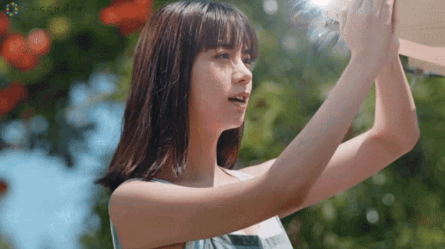 a woman in a blue tank top is looking up at something