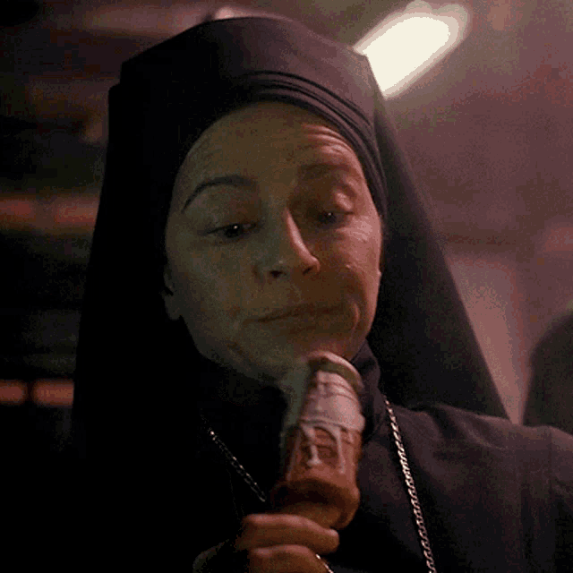 a nun is eating an ice cream cone with a white frosting on it