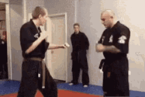 two men in black karate uniforms are standing in a gym