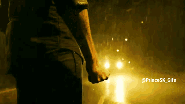 a man in a black shirt is standing in the rain with his fist in the air