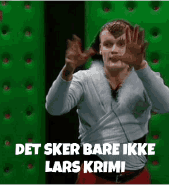 a man is standing in front of a green wall with his hands up and the words det sker bare ikke lars krimi .