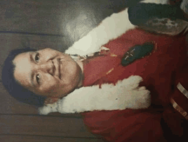a man in a red jacket with a white fur collar is smiling