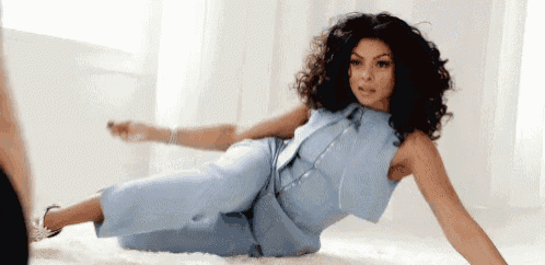 a woman in a light blue jumpsuit is laying on the floor .