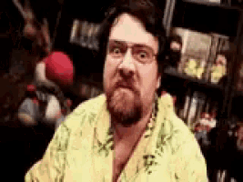 a man with glasses and a beard is making a funny face .