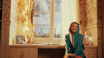 a girl sits in front of a burning window