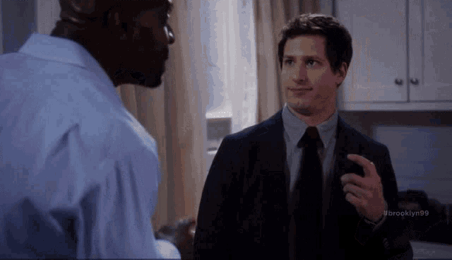 a man in a suit and tie is talking to another man in a blue shirt ..