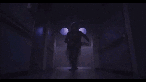 a blue monster is standing in a dark hallway and looking at the camera