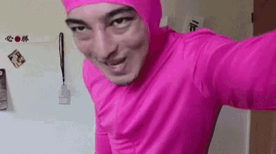 a man in a pink suit is taking a selfie in a room .