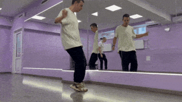 a man in a white shirt is dancing in front of a large mirror