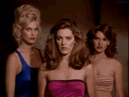 three beautiful women are standing next to each other in a dark room .